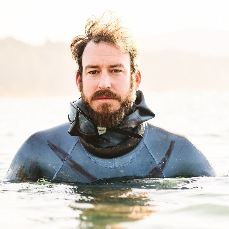 Freediver Grant Hogan chest-deep in water against bright sunlight